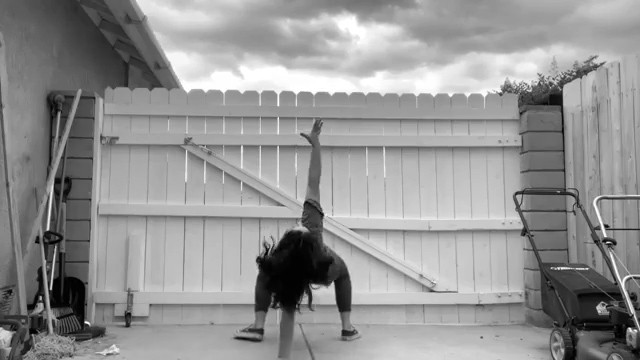 dancer Emily in front of a gate and tools for yardwork