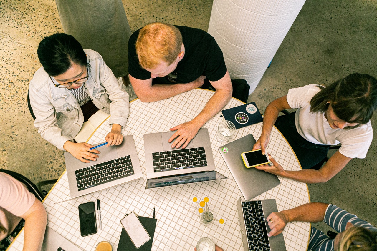 diverse group of people using laptops around a table